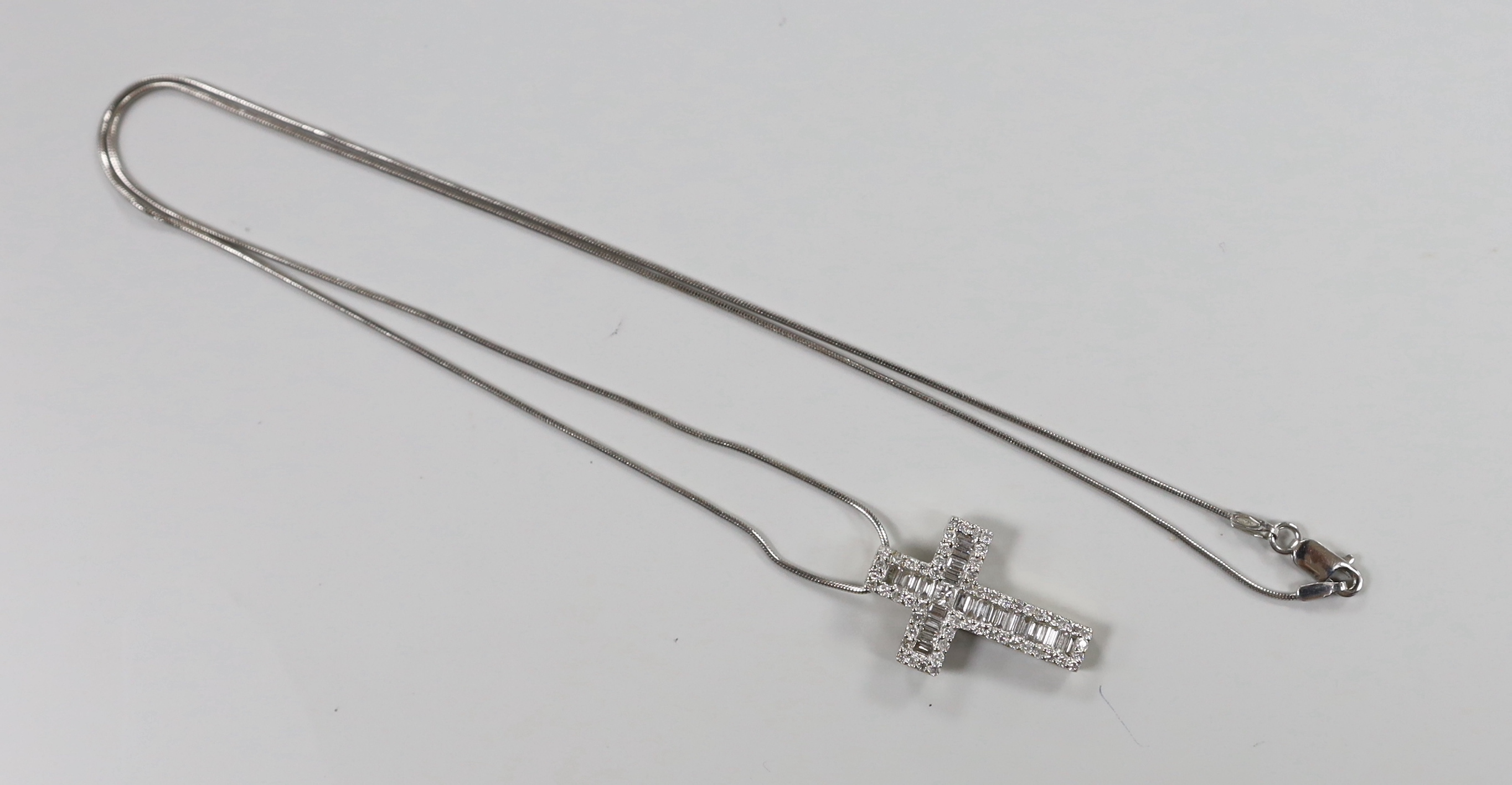 A modern 750 white metal, baguette and round cut diamond cluster set cross pendant, 23mm, gross 3.1 grams, on a 375 white metal fine chain, 46cm, 2.6 grams.